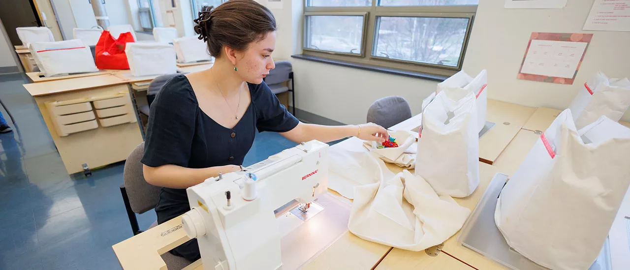 Fashion student preparing to sew fabric using a sewing machine.