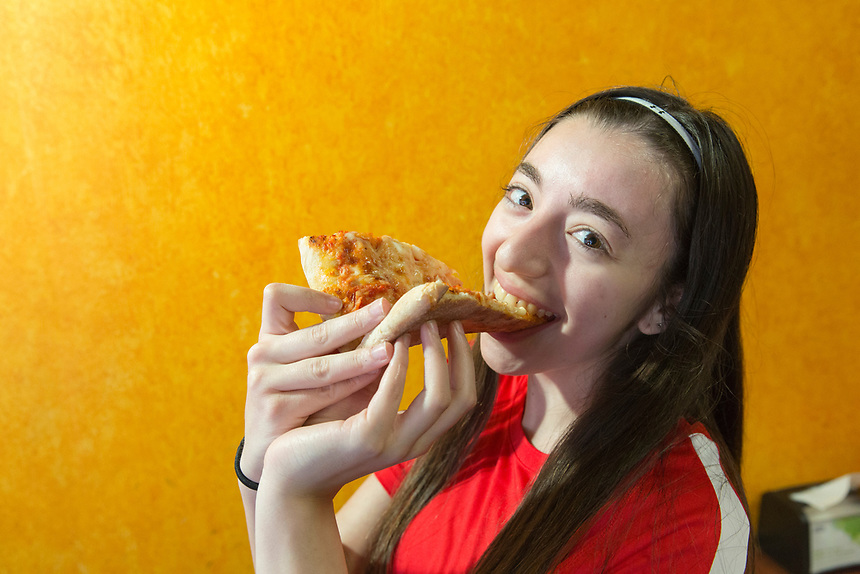 Student biting into a slice of pizza