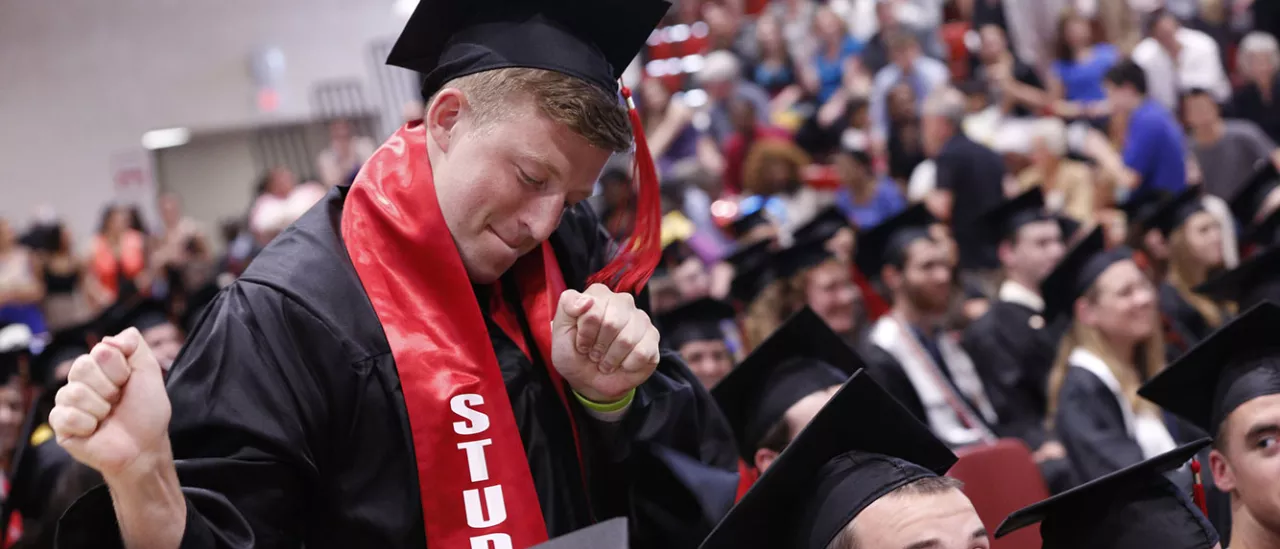 Student dancing in their cap in gown at graduation.