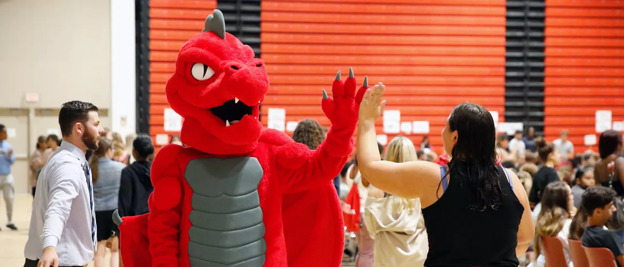 Red the dragon high fiving a new student