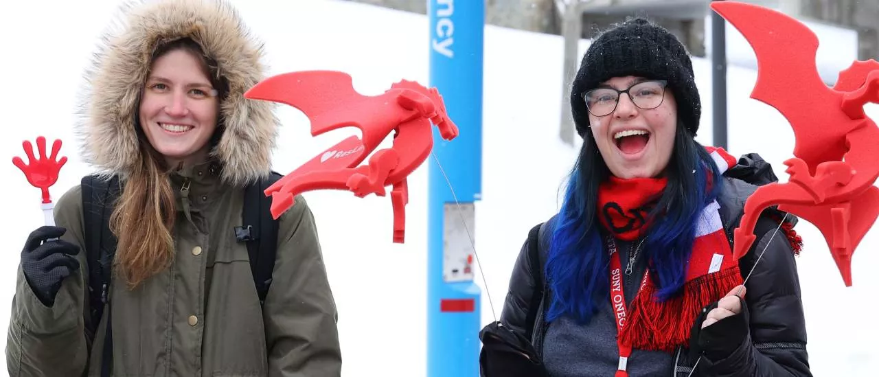 Two students smiling while holding Dragon standees at the Pass Through the Pillars event.