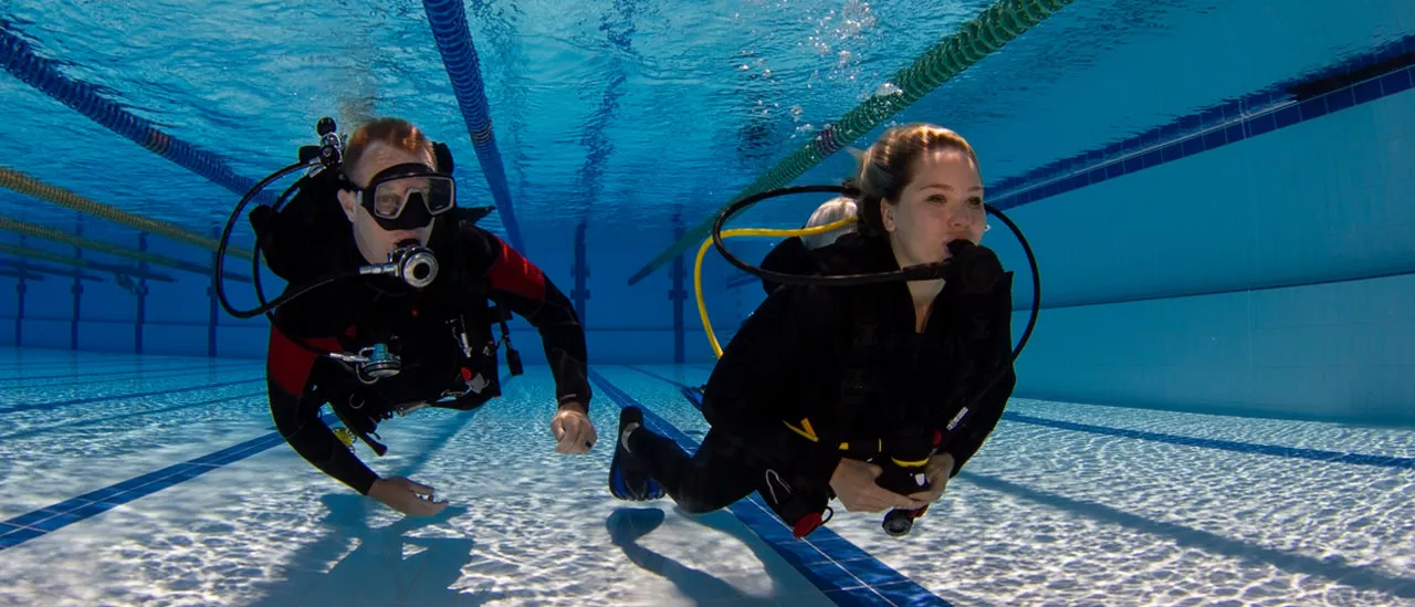 2 SCUBA divers swimming in a pool