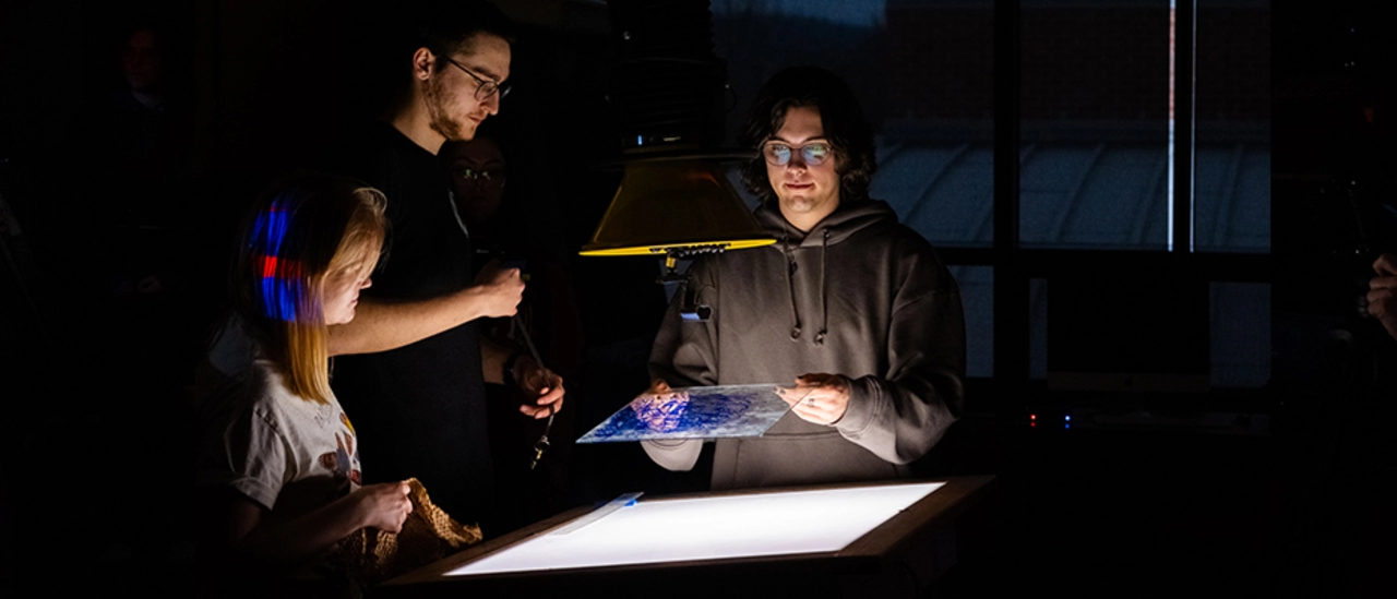 Three student interns interact with Collaborative Artwork