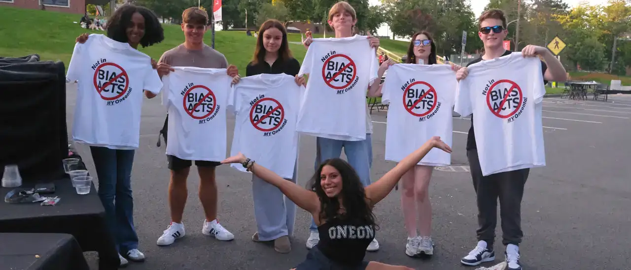 Group of students holding up bias acts not in my Oneonta t shirts.