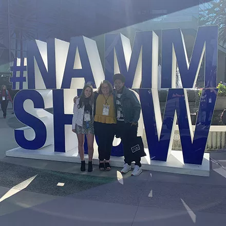 three students in front of NAMM Show sign
