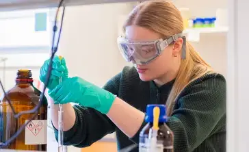 A female biochemistry student in the lab mixing chemicals