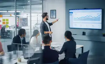 A business analyst reviews data with a group of investors