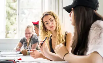 Group of students engaged in a lively discussion in a bright classroom setting.