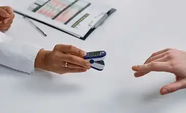 Healthcare provider putting a pulse oximeter on a patient's finger.