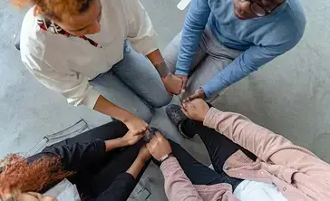 Overhead view of students holding hands in a tight group.