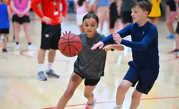 A child defends while dribbling during youth basketball camp.