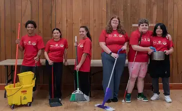 First-year and transfer students pose with their cleaning tools during a day of of community service.