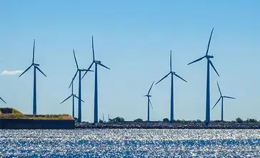 Offshore wind turbines stand over a waterway.