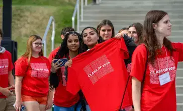 SUNY Oneonta Class of 2029 students pose with a vivid red t-shirt during Pass Through the Pillars.
