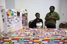 Student members of the Caribbean Student Association sit at a table decorated with colorful flags.