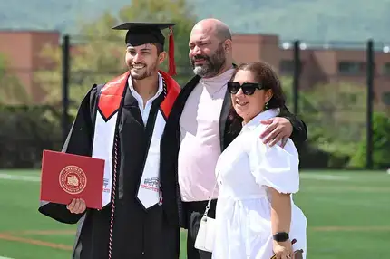 Graduate posing for a photo with their family on a sunny day