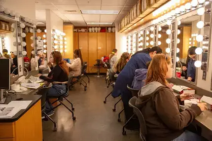 Students work on makeup in the theatre dressing room.