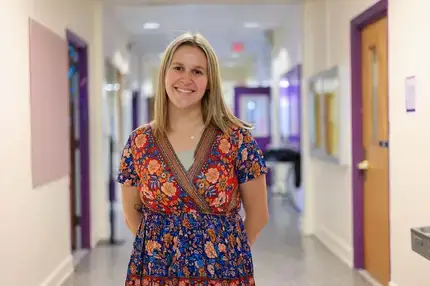 Carolyn Muller, M.S.Ed.-Literacy Education graduate, posing for a phoo in the hallway of a local elementary school
