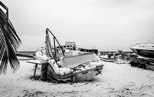 Black and white photo of a dammaged boat on a beach