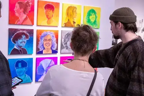 Patrons discuss colorful prints at the 2025 Juried Student Art Show.