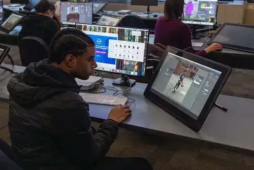 A student works on two screens during a 3D graphics class.