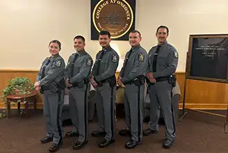 Five newly graduated police instructors pose, arranged by height.