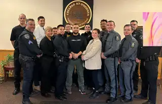 Fourteen new Police Field Training Officers pose with an instructor for a graduation photo.