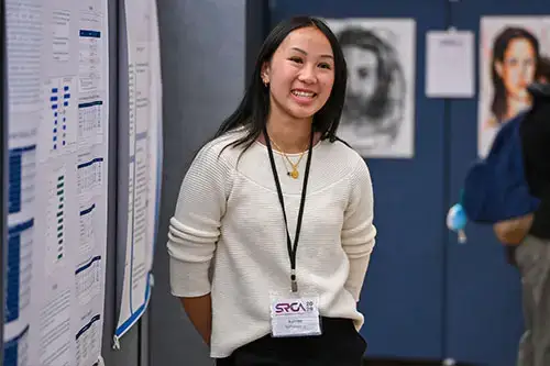 Student standing next to their SRCA research poster