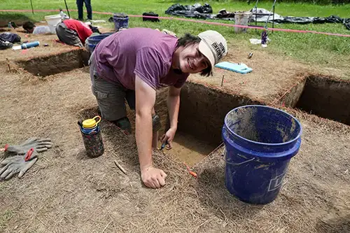 Archaeology student digs for artifacts