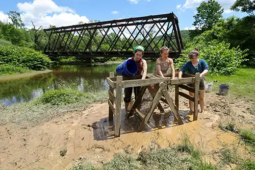 Archaeology students shift through mud