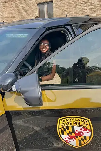 Ari Boyd poses in Maryland state police car