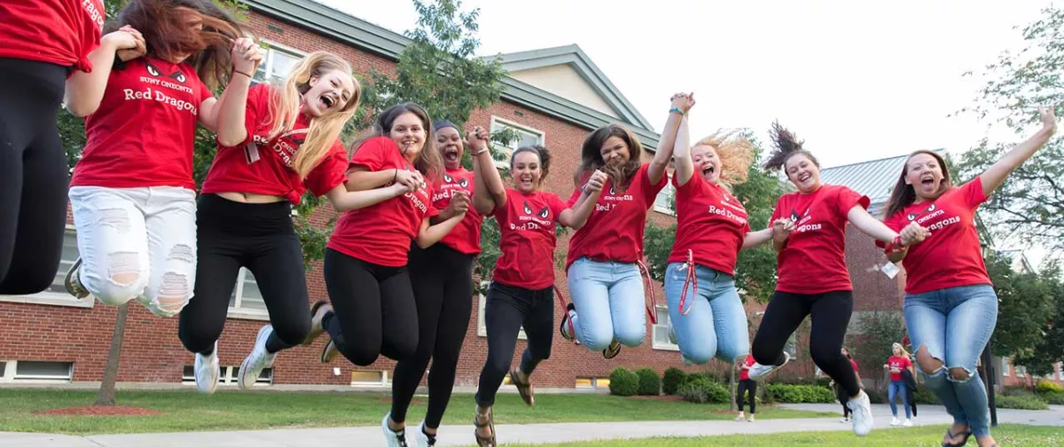 Students jump in the air in front of Wilber Hall