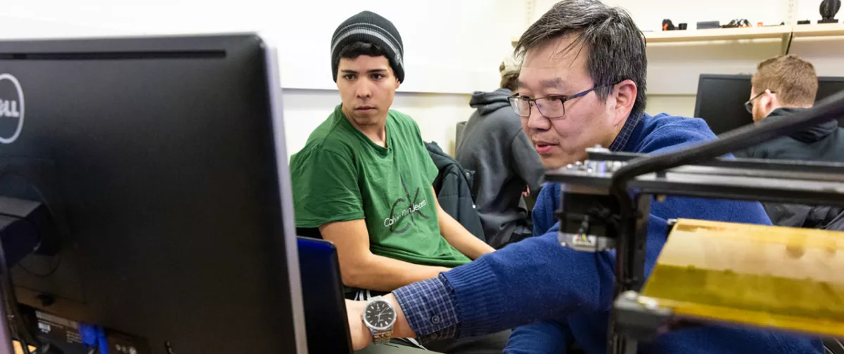 Student and faculty member working on a computer.