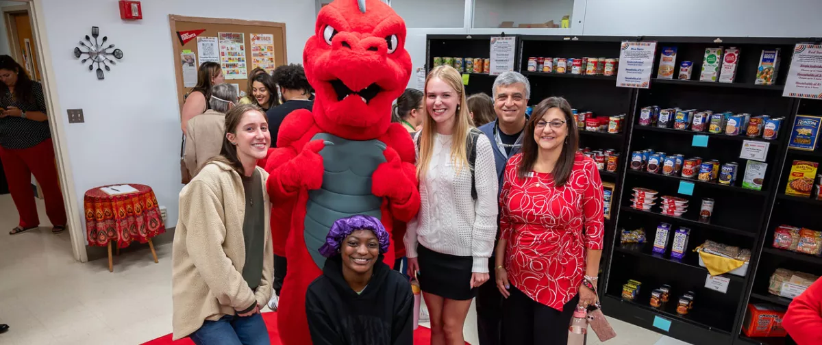 Red the Dragon with a group of students and staff at the food pantry