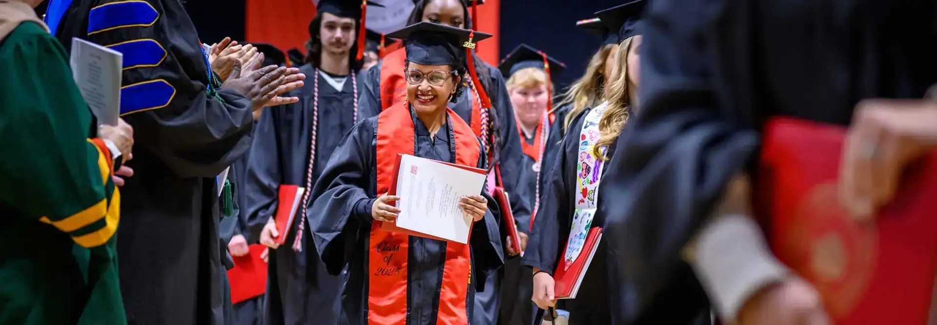 Maria Lopez holds up her diploma at Fall Commencement