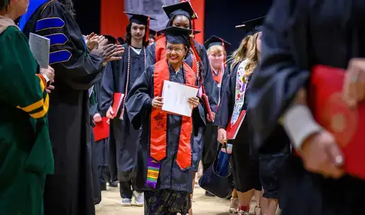 Maria Lopez holds up her diploma at Fall Commencement