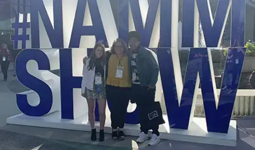 three students in front of NAMM Show sign