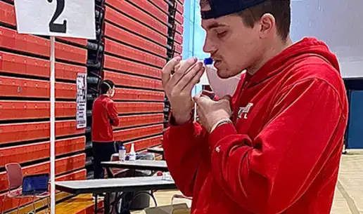 Student doing a COVID-19 saliva test at the Alumni Field House pool testing center