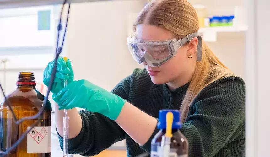 A female biochemistry student in the lab mixing chemicals