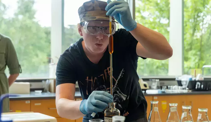 Chemistry student carefully measures a chemical sample for testing.