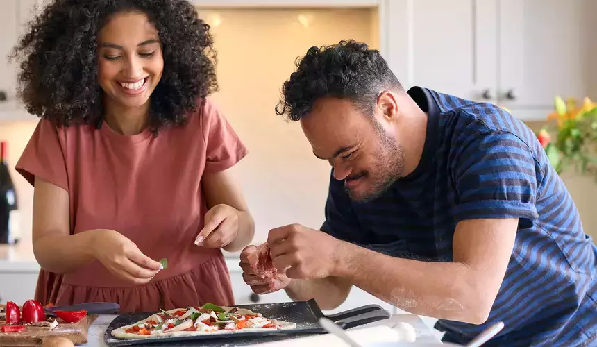 Woman works with special needs individual in the kitchen