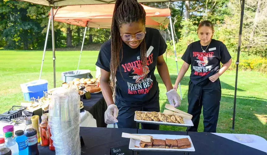 Food service major places trays of food on table at Red Dragon Open