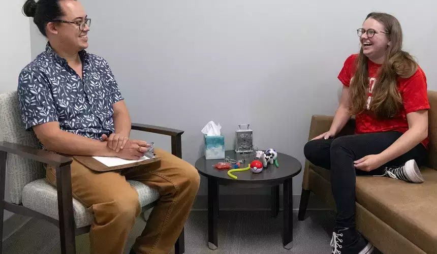 School counselor meets with smiling student in their office. 