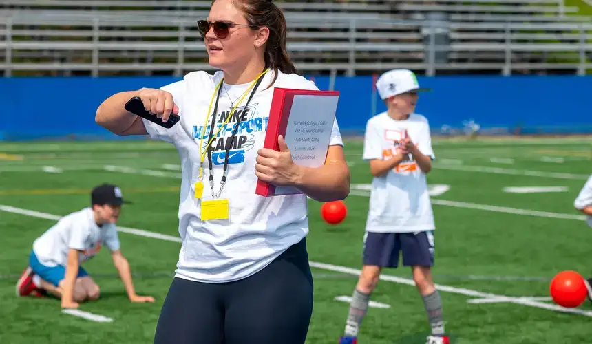 Sports Management student directs young students at a soccer training camp.