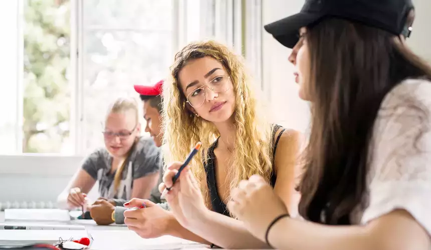 Group of students engaged in a lively discussion in a bright classroom setting.