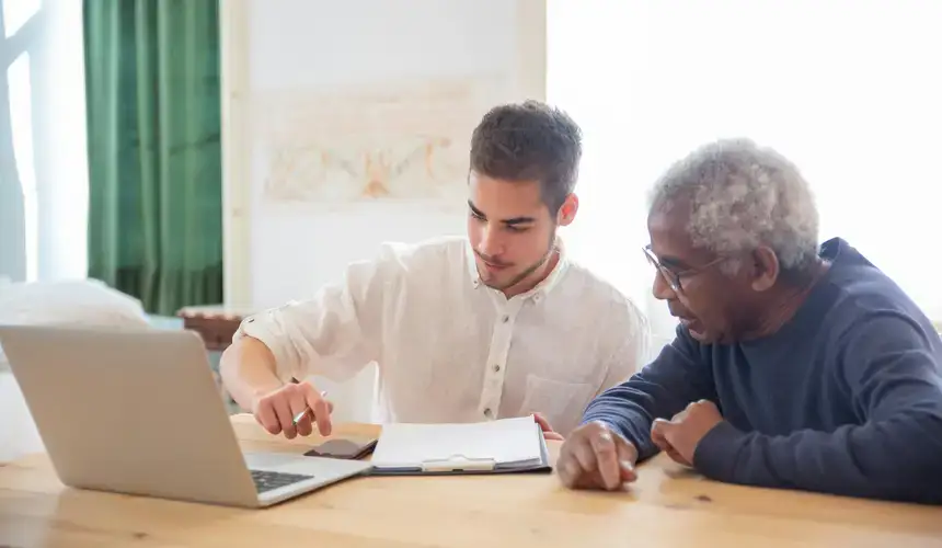 Younger individual helps older person with life skills.