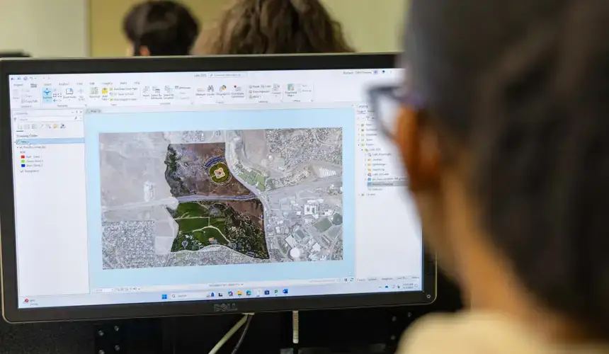 GIS student reviews map data on screen.