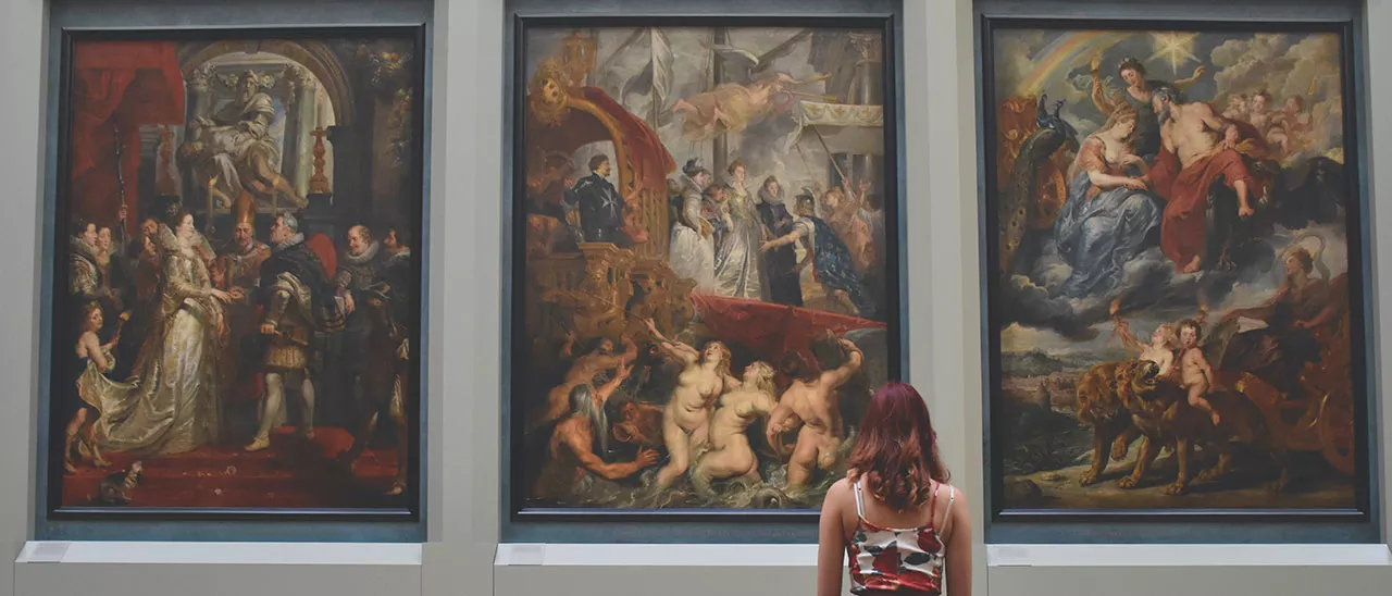 Museum Studies student admiring paintings in a museum.