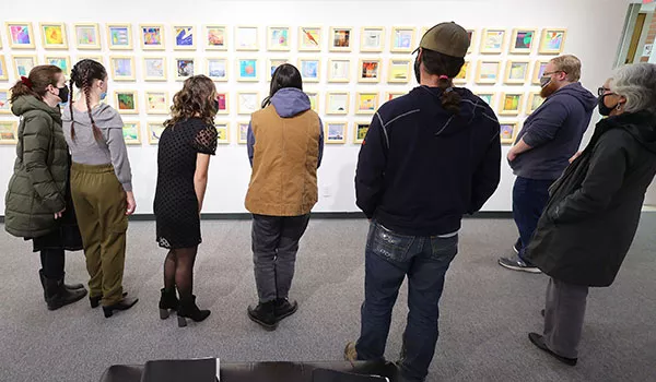 Crowd of people admiring various paintings in a gallery