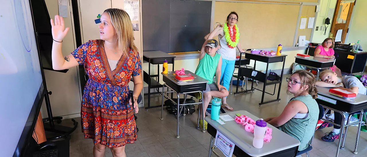 Carolyn Muller using a projector to teach a classroom of children.